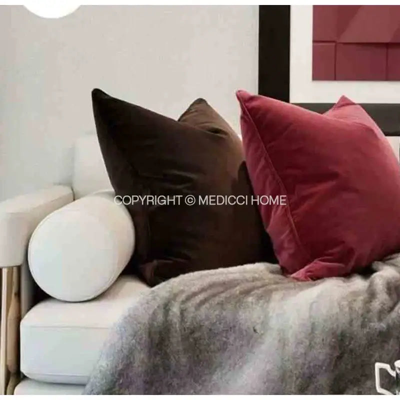 Two plush decorbites luxe italy velvet pillowslips in deep brown and burgundy red on a white living room sofa