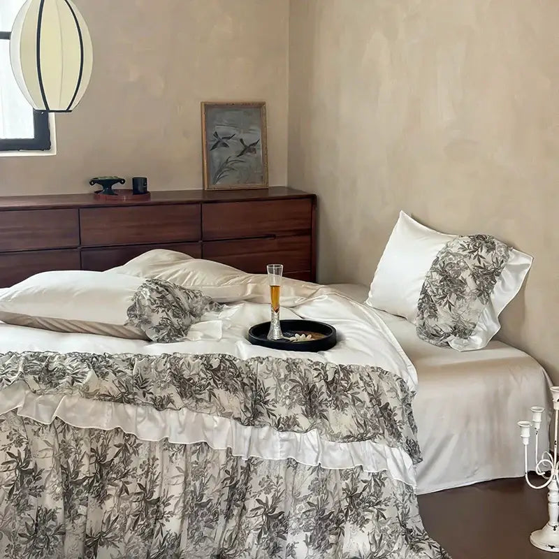 The decorbites luxe lace ruffles bedding set features a black and white botanical ruffled duvet cover over white satin sheets