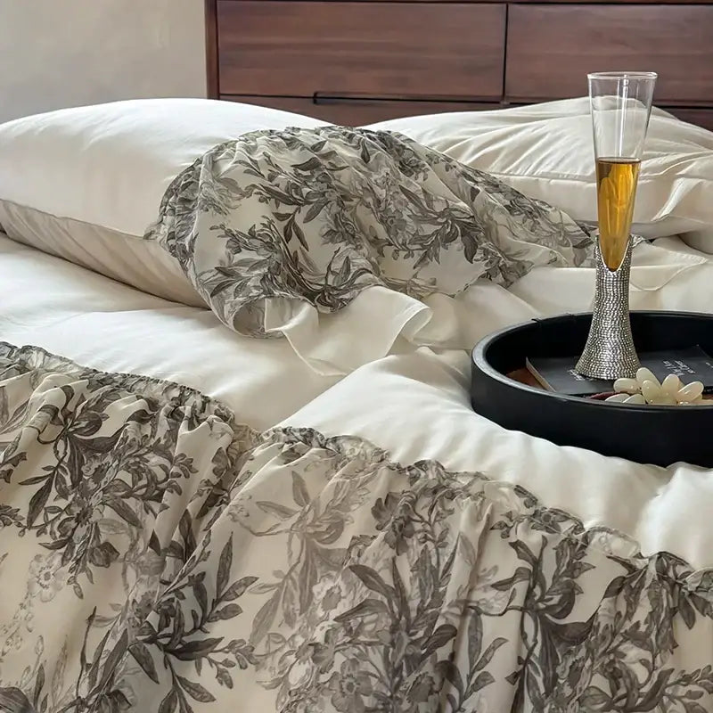 A champagne flute with a diamond-encrusted stem on a black tray beside the decorbites luxe lace ruffles bedding set