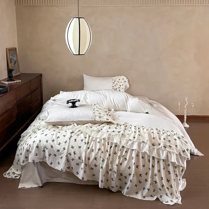 Cream-colored satin bed skirt with black butterfly prints and layered ruffles from decorbites luxe lace bedding set