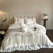 White satin bedding set with delicate pink floral embroidery and ruffled edges from decorbites luxe lace ruffles collection