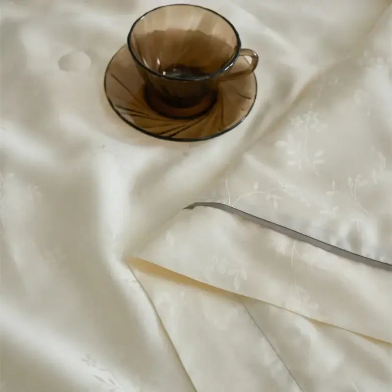 A translucent amber glass teacup with radial etching on a decorbites luxe lyocell summer blanket with mulberry silk fill