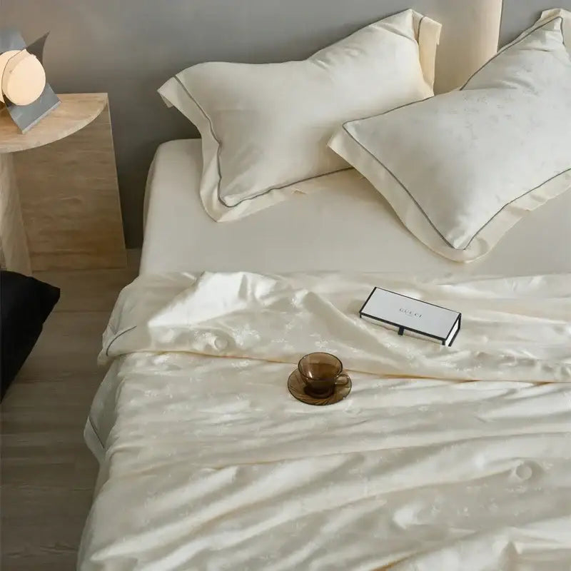 Cream-colored decorbites luxe lyocell summer blanket with subtle texture and matching pillowcases filled with mulberry silk