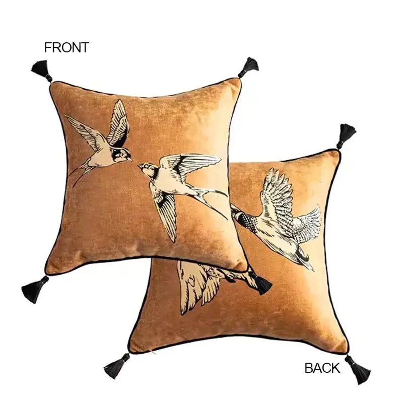 Warm gold velvet decorative pillow case with elegant black and white bird illustrations and black tassels by DecorBites