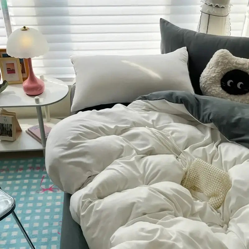 A cream-colored beaded crossbody bag with a delicate chain strap on a bed with a cotton bedding set decorbites