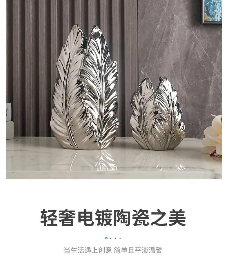 Two silver electroplated ceramic leaf sculptures with detailed veining complement luxurious gold ceramic vases for home decor