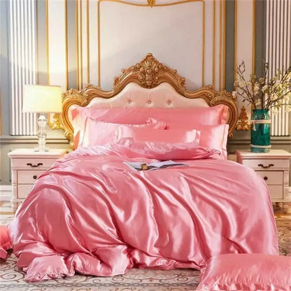 Pink satin mulberry silk bedding set with matching duvet cover and pillows featuring an ornate gold headboard