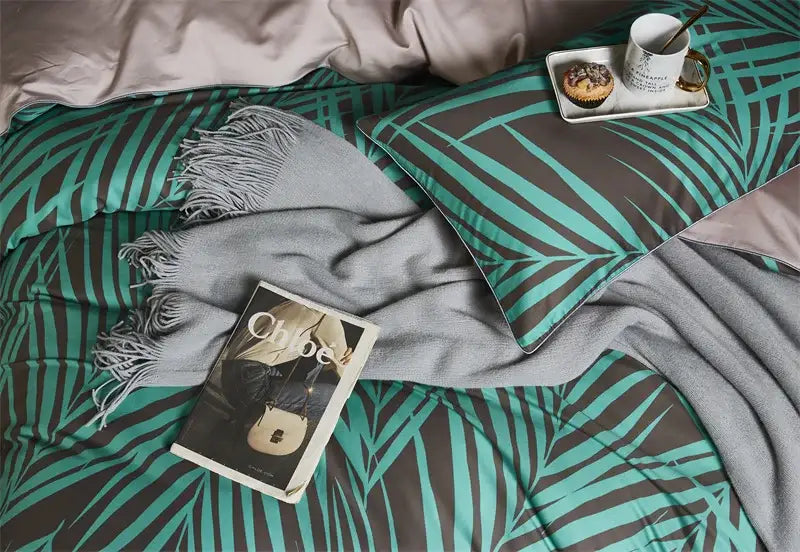 Teal and dark gray palm leaf patterned duvet cover and pillowcases with a soft fringed gray throw in egyptian cotton