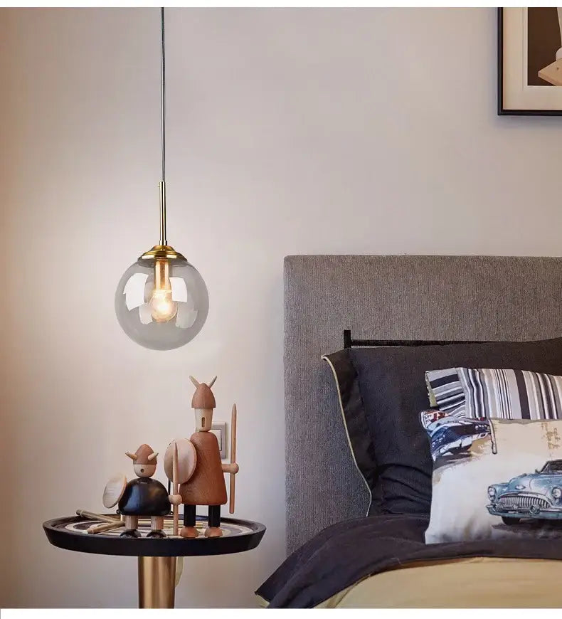 A luxury nordic led chandelier with clear glass globe and brass accents hanging above a dining room table