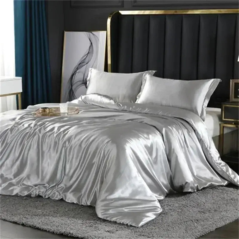 Silver satin duvet cover bedding set with matching pillowcases and fitted sheet featuring luxurious sheen and smooth texture
