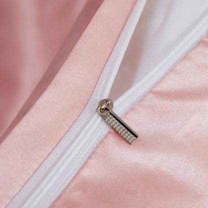 A silver-toned zipper pull with a textured pattern on a solid color soft pink pcduvet cover from decorbites luxury satin bedding set