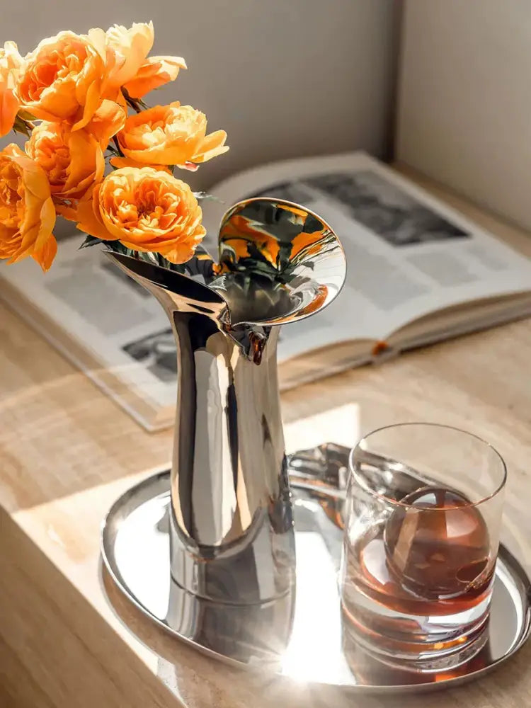 Decorbites luxury stainless steel vase with a shiny metallic finish and flared opening holding vibrant orange roses