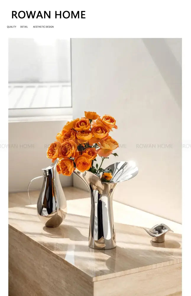 DecorBites luxury stainless steel vase in sleek silver with a sculptural design holding vibrant orange roses