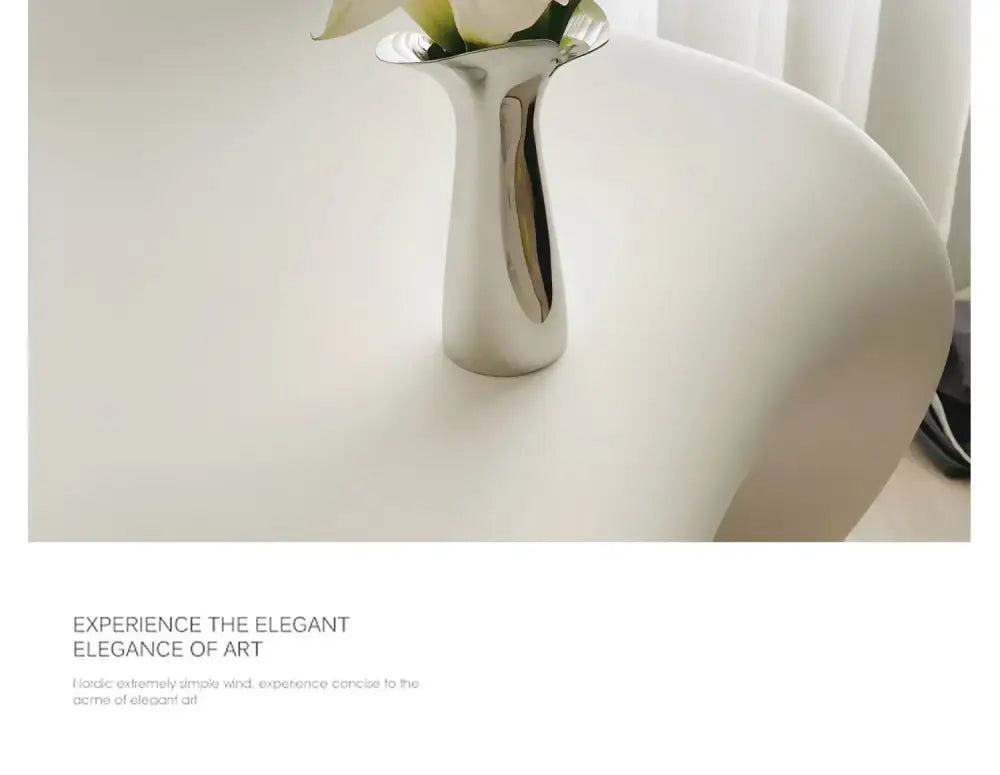 Decorbites luxury stainless steel vase in sleek silver metallic with modern sculptural design holding white flowers