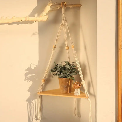 Beige macrame wall hanging corner shelf with wooden accents and a small plant for boho decor by decorbites
