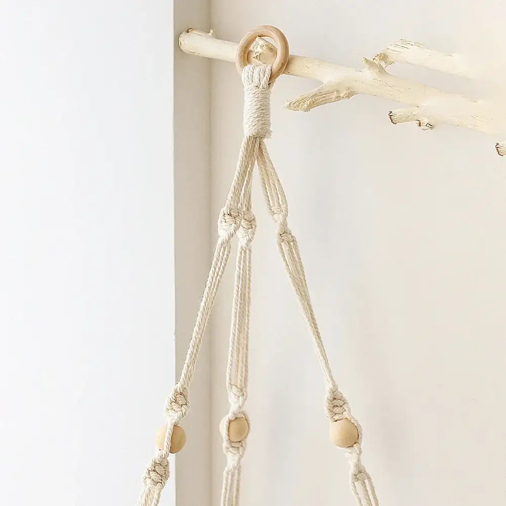 Cream-colored macrame wall hanging corner shelf with wooden beads and natural wood ring for boho decor by decorbites