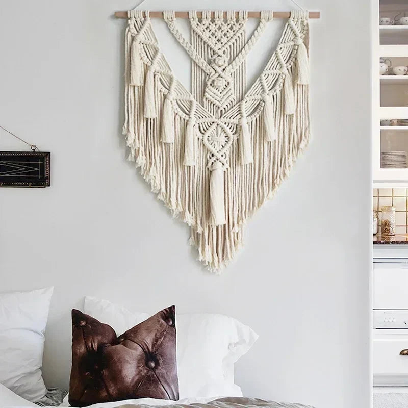 Cream-colored macrame wall hanging with intricate woven patterns and long fringe tassels for chic bohemian decor