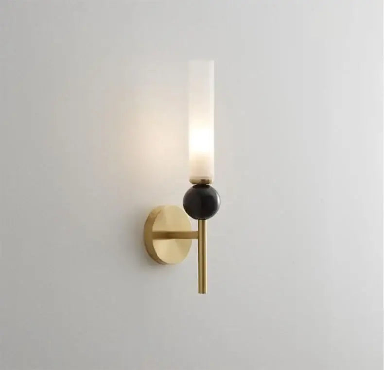 Gold-toned decorbites marble sconce wall light with frosted glass cylinder and matte black spherical accent