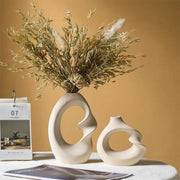 Cream-colored matte ceramic vase with sculptural curves and central cutout in DecorBites™ vase set for home decor