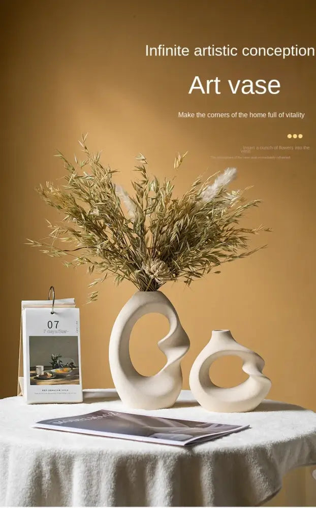 Cream-colored matte ceramic vase set with abstract flowing curves and central opening for modern home decor