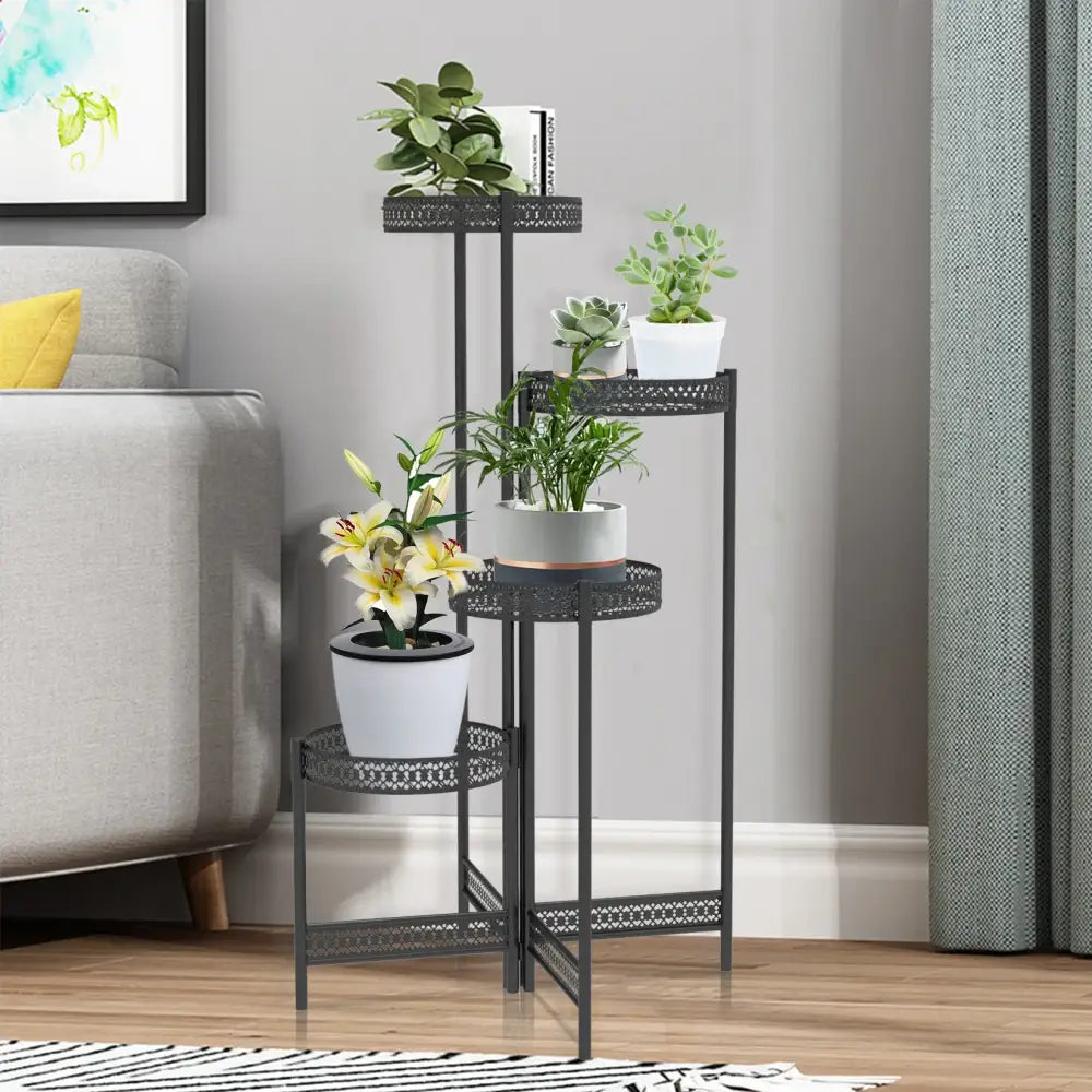 Black metal plant stand DecorBites with three decorative lattice tiers holding various potted plants for living room use