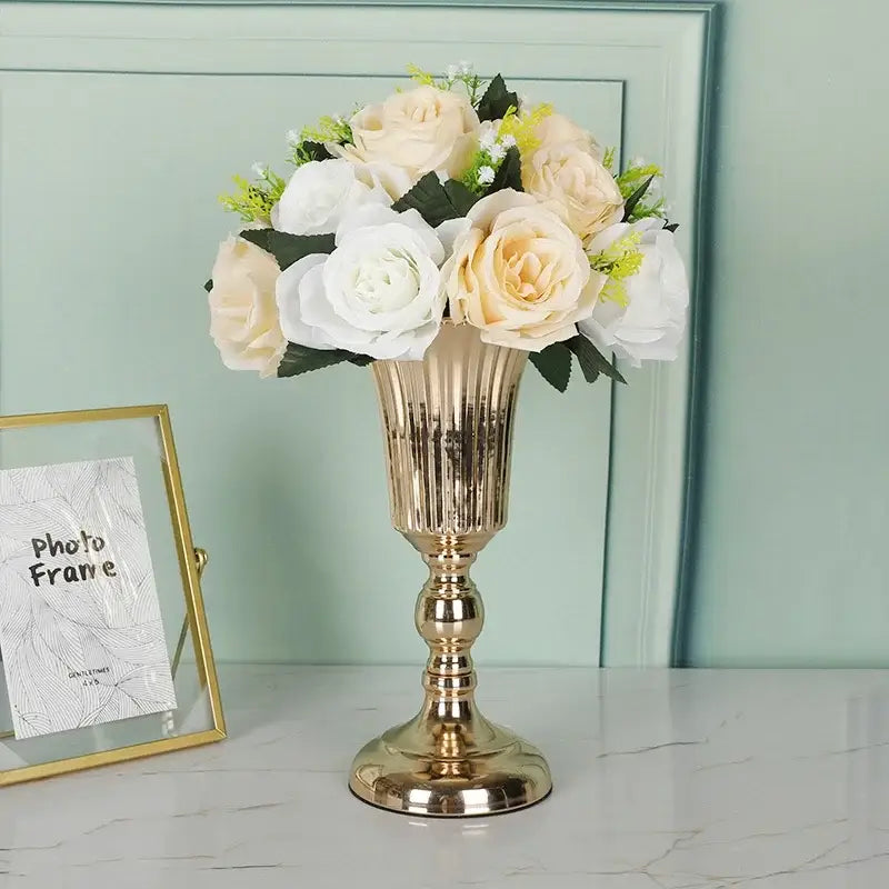 DecorBites metal trumpet vase in gold metallic fluted design holding cream white artificial roses with green leaves