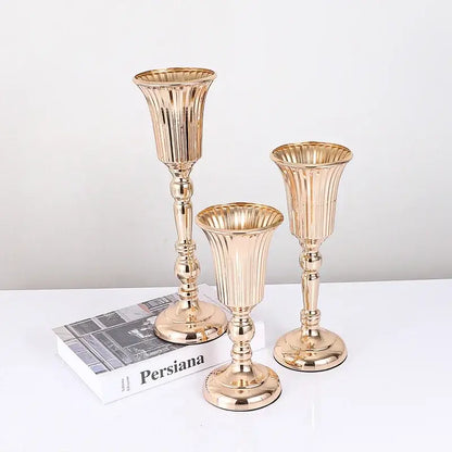 Set of three gold-toned metal trumpet vase candle holders with fluted ribbed detailing for wedding centerpiece decor