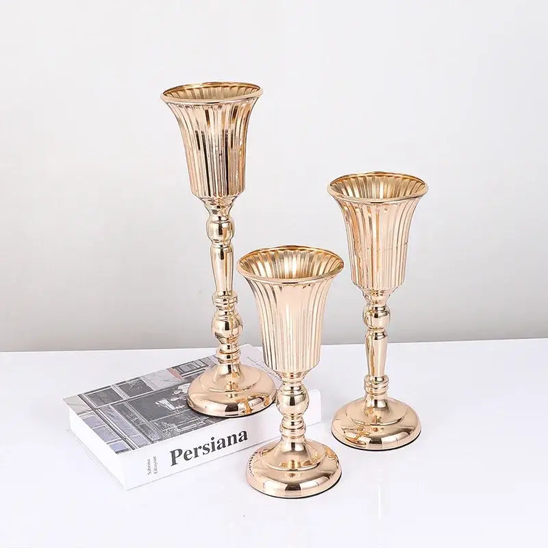 Set of three gold-toned metal trumpet vase candle holders with fluted ribbed detailing for wedding centerpiece decor