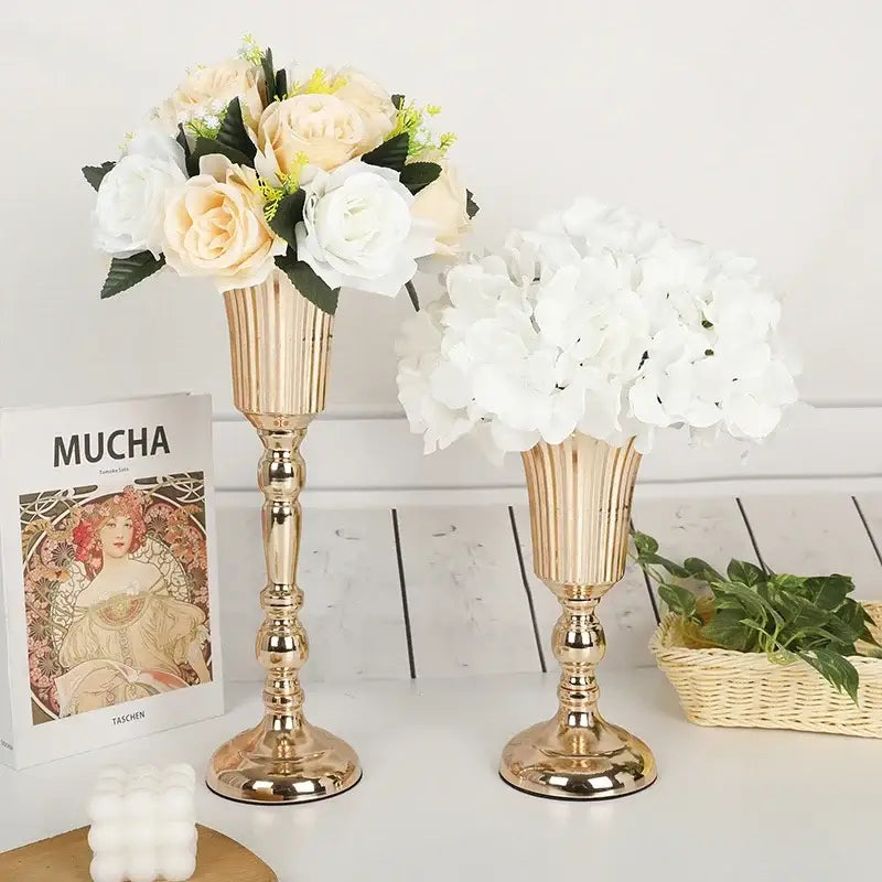 Two elegant gold-toned metal trumpet vases with cream roses and white hydrangeas for wedding centerpiece decor
