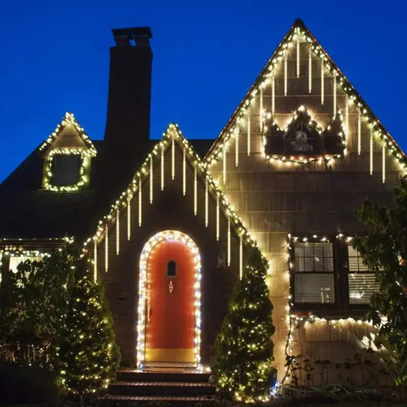 A warmly lit festive house decorated with decorbites™ meteor shower led string lights featuring cascading white icicle lights