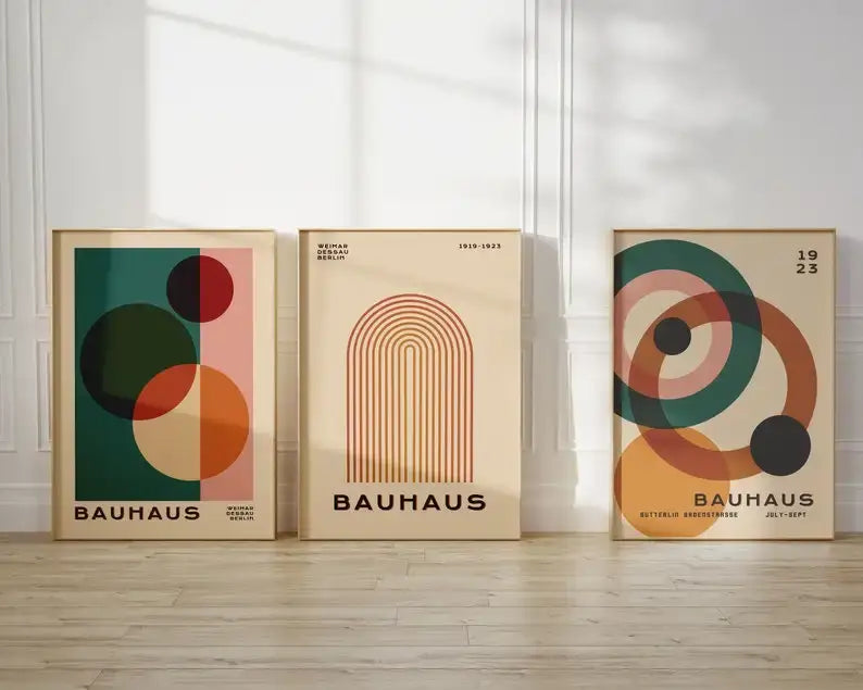 Three framed mid century modern bauhaus-style posters with geometric designs in earth tones and bold primary colors