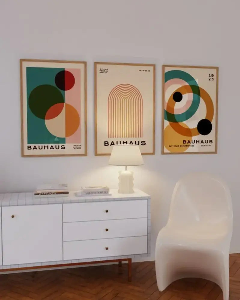 Set of three framed bauhaus-style mid century modern posters with geometric designs in muted teal orange and cream tones