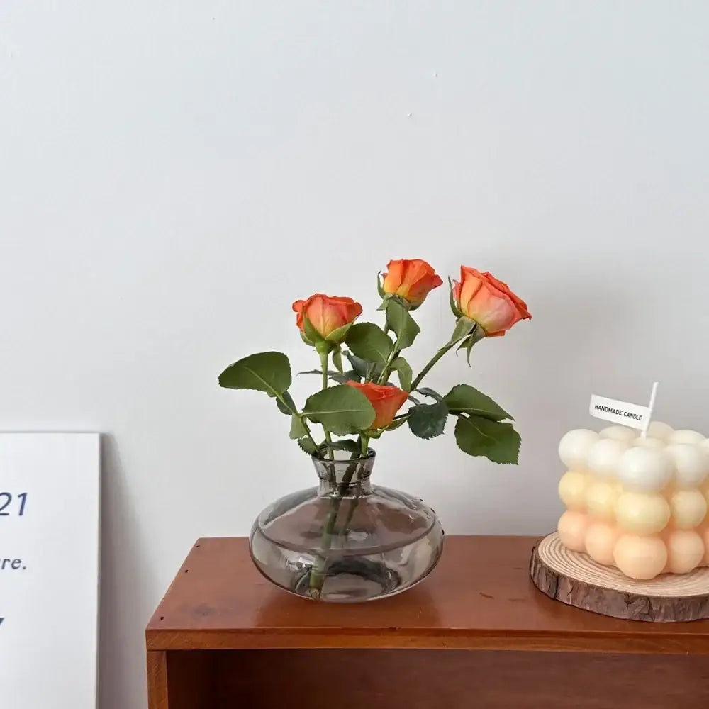 DecorBites™ mini glass flower vase with rounded base and narrow neck holding orange roses for home decor