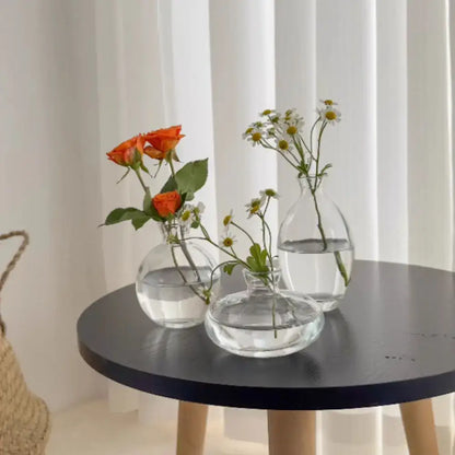 Three clear glass mini flower vases of varying shapes holding fresh flowers for home decor by decorbites