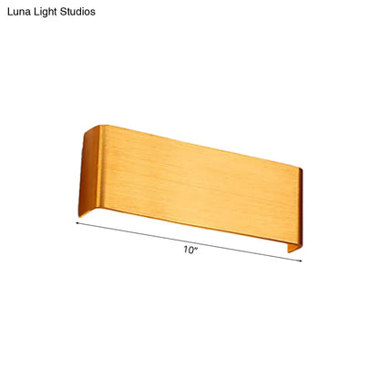 A sleek brushed gold rectangular wall lamp with minimalist design providing warm white light for living room use