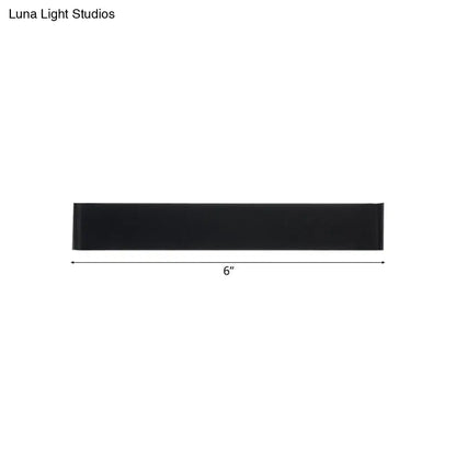 Black rectangular wall lamp 6 inches long with silver accents providing warm white light for living room use
