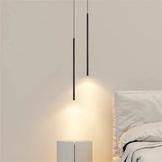 Two sleek black DecorBites™ modern 2cm led pendant lights hang over a minimalist bedside table and bed casting warm glow