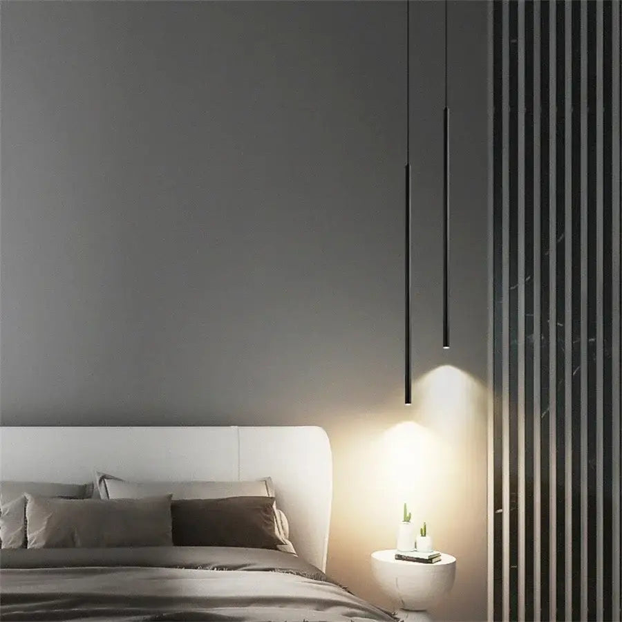 Two sleek black DecorBites 2cm led pendant lights hang casting warm light over bedside table