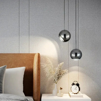 Two chrome-finished spherical decorbites™ modern adjustable led pendant lights hang above a white nightstand