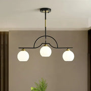Modern arched island pendant light with clear white glass globe shades and black brass finish in a three-light design