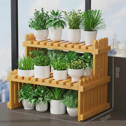 Light brown bamboo two-tier plant display stand with picket fence design holding white ceramic pots with green plants