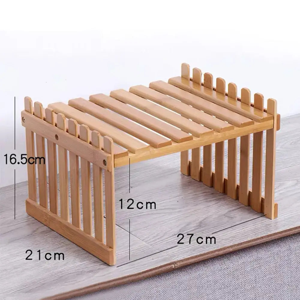 Light brown bamboo garden bench with slatted top and vertical picket sides used as a plant display stand