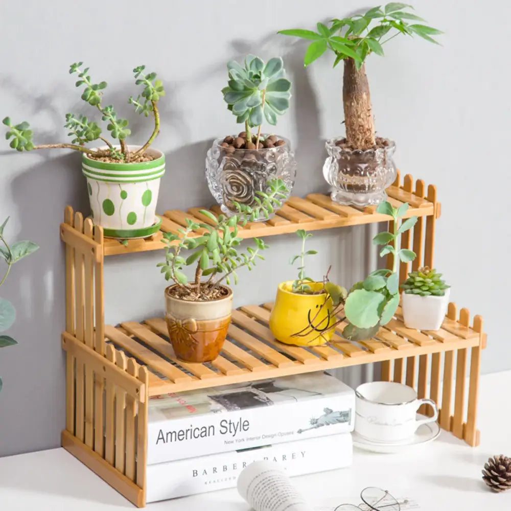 Light brown bamboo two-tier plant display stand with vertical slat sides and decorative picket-style edges by DecorBites