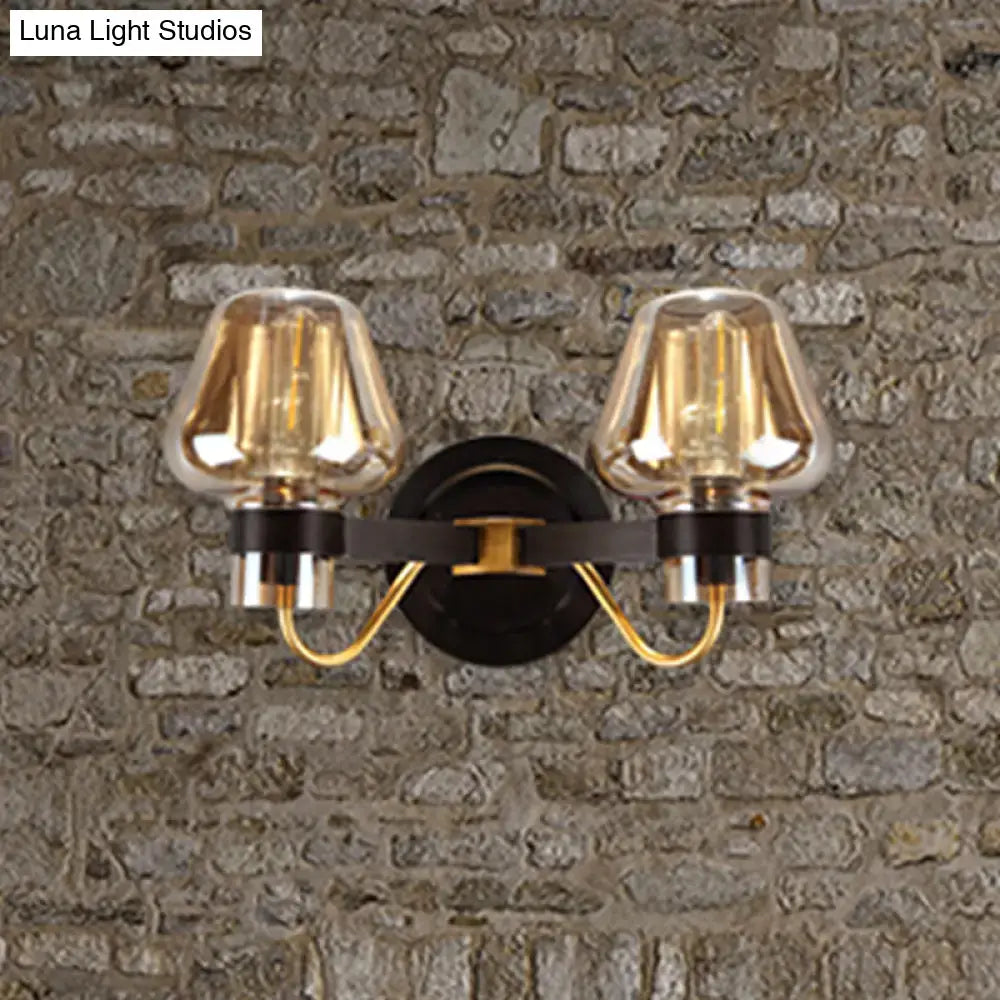 Modern black and gold mushroom sconce light fixture with amber glass shades and black metal arms for living room use