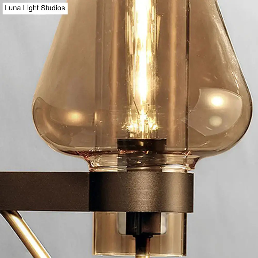 Modern black and brass wall sconce with amber glass and visible filament bulb for bedroom lighting
