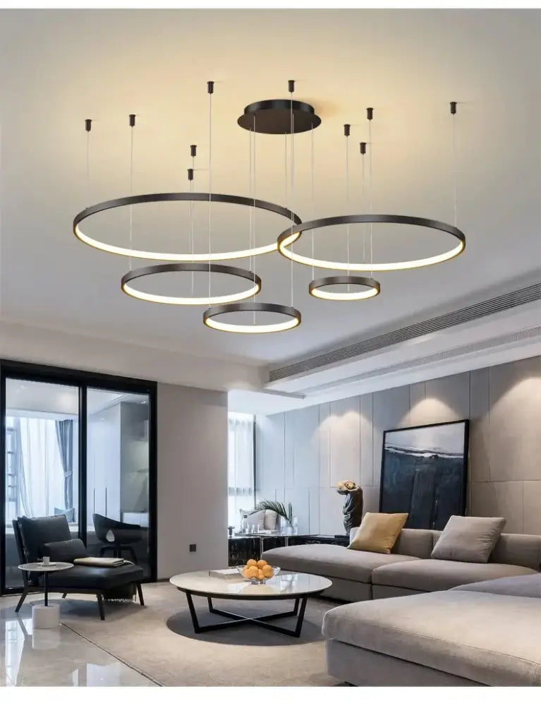 Modern black pendant light featuring illuminated circular rings hanging in a living room for dimmable ambiance