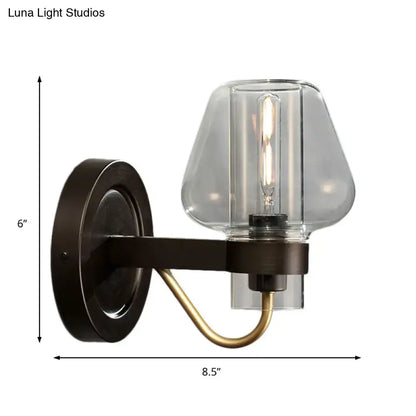 Modern black and brass wall sconce with glass mushroom shade featuring a dark bronze base and clear glass filament bulb