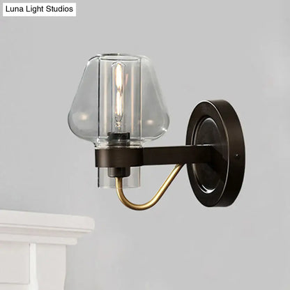 Modern black and brass wall sconce with glass mushroom shade featuring a clear glass and exposed filament bulb