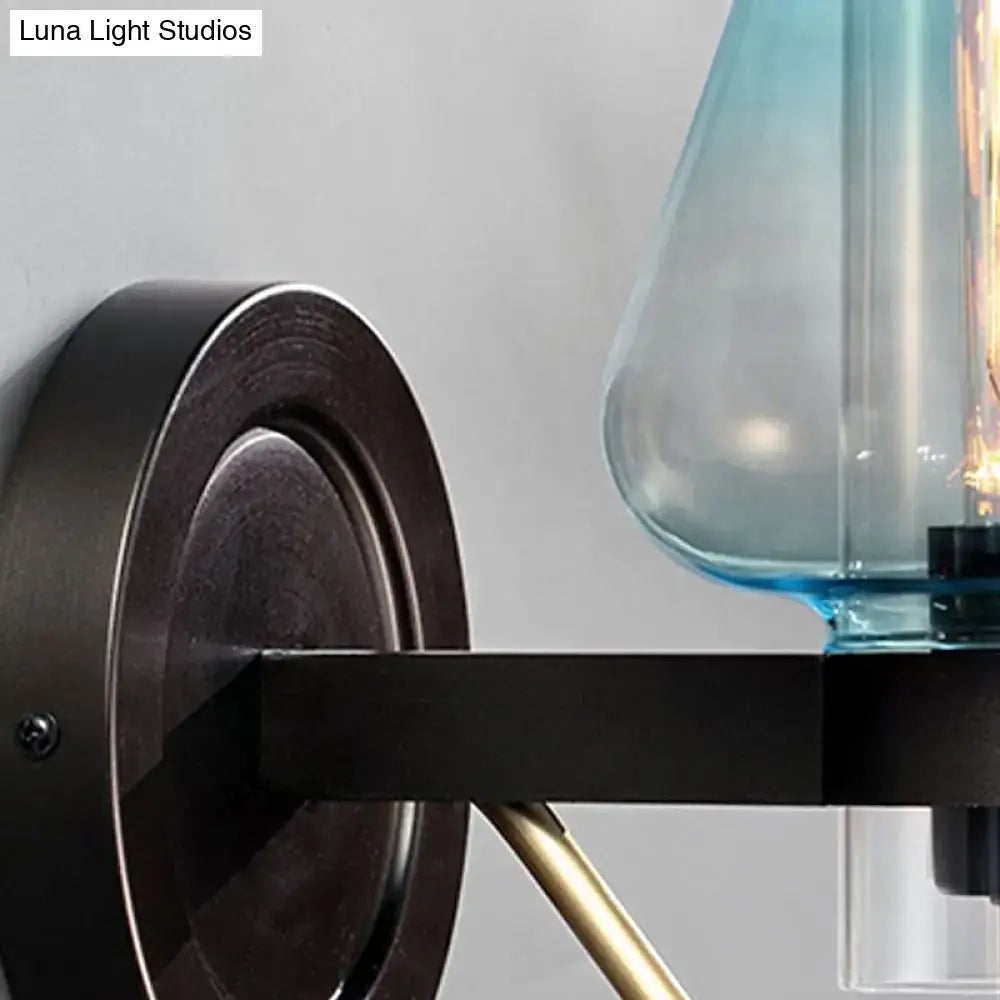 Modern blue glass wall sconce light fixture with tapered shade mounted on black metal arm with brass accents for bedroom wall