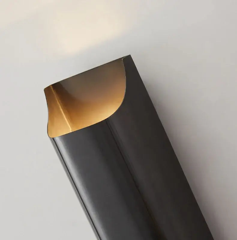 Black cylindrical trash can with a gold-toned curved lid shown alongside decorbites modern brass led wall lamp